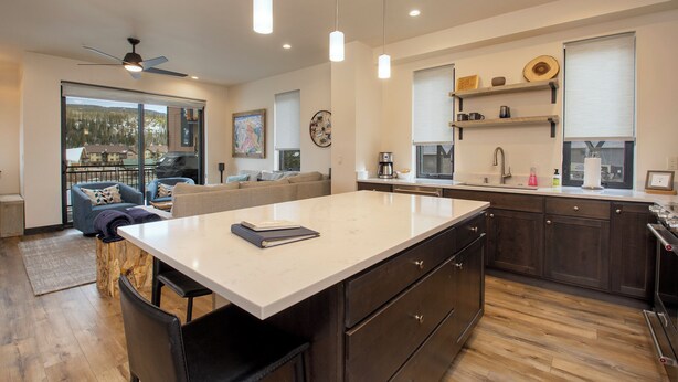A modern kitchen with a large island, dark wood cabinets, and pendant lighting. - Arrow at Winter Park Unit 248 Downtown 4 bedroom private hot tub & mountain view (Winter Park)