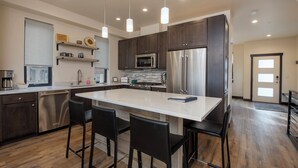 A modern kitchen with dark wood cabinets, stainless steel appliances, and pendant lighting. - Arrow at Winter Park Unit 248 Downtown 4 bedroom private hot tub & mountain view (Winter Park)