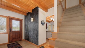 Un intérieur moderne avec un escalier en bois, un mur d’accent noir et une vue sur l’extérieur.
