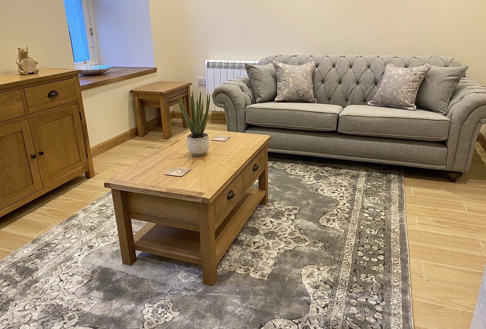 A living room with a sofa, wooden coffee table, and a patterned rug.