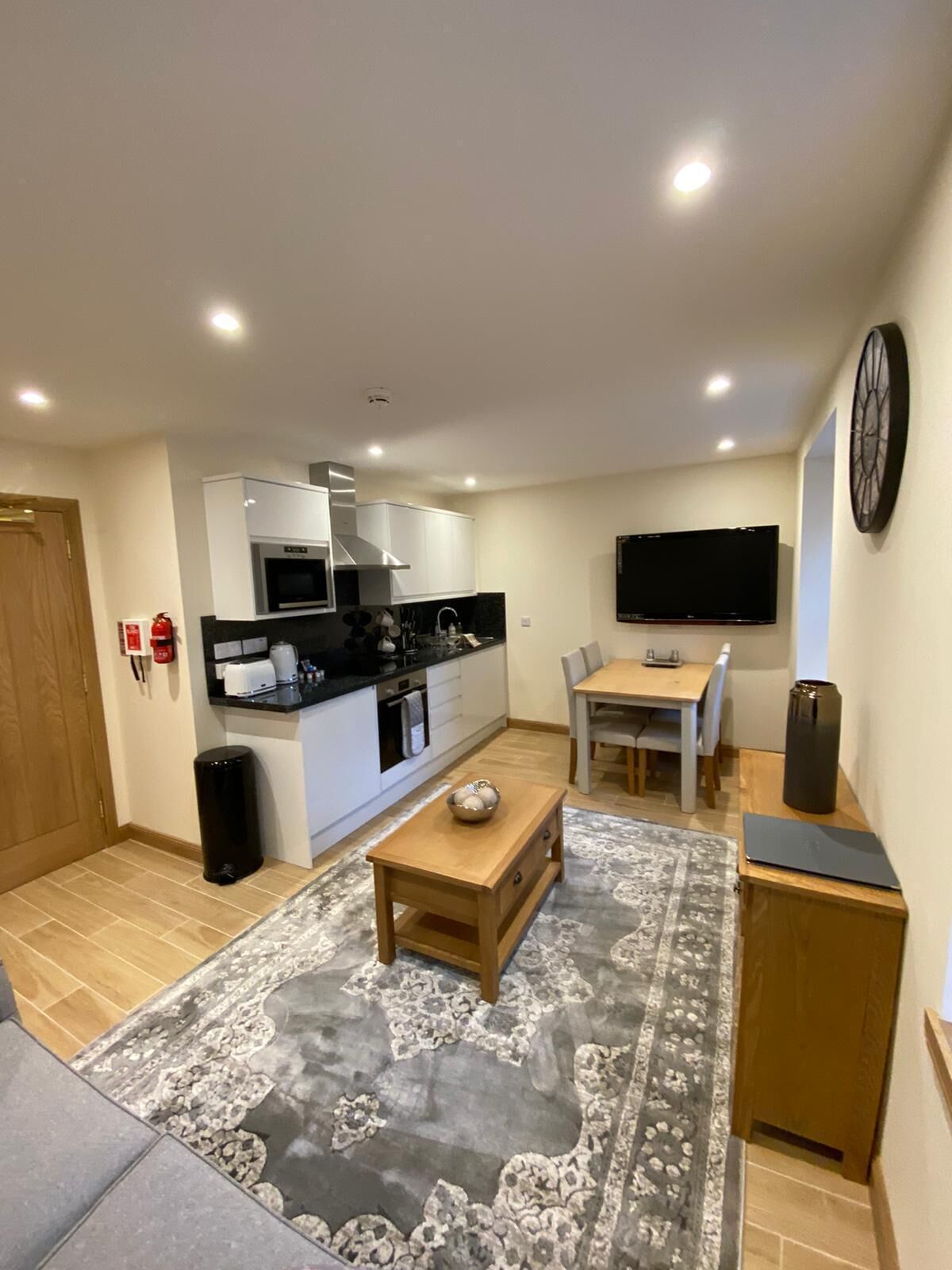 Un espacio habitable compacto con kitchenette, comedor y zona de estar con un tapete estampado.