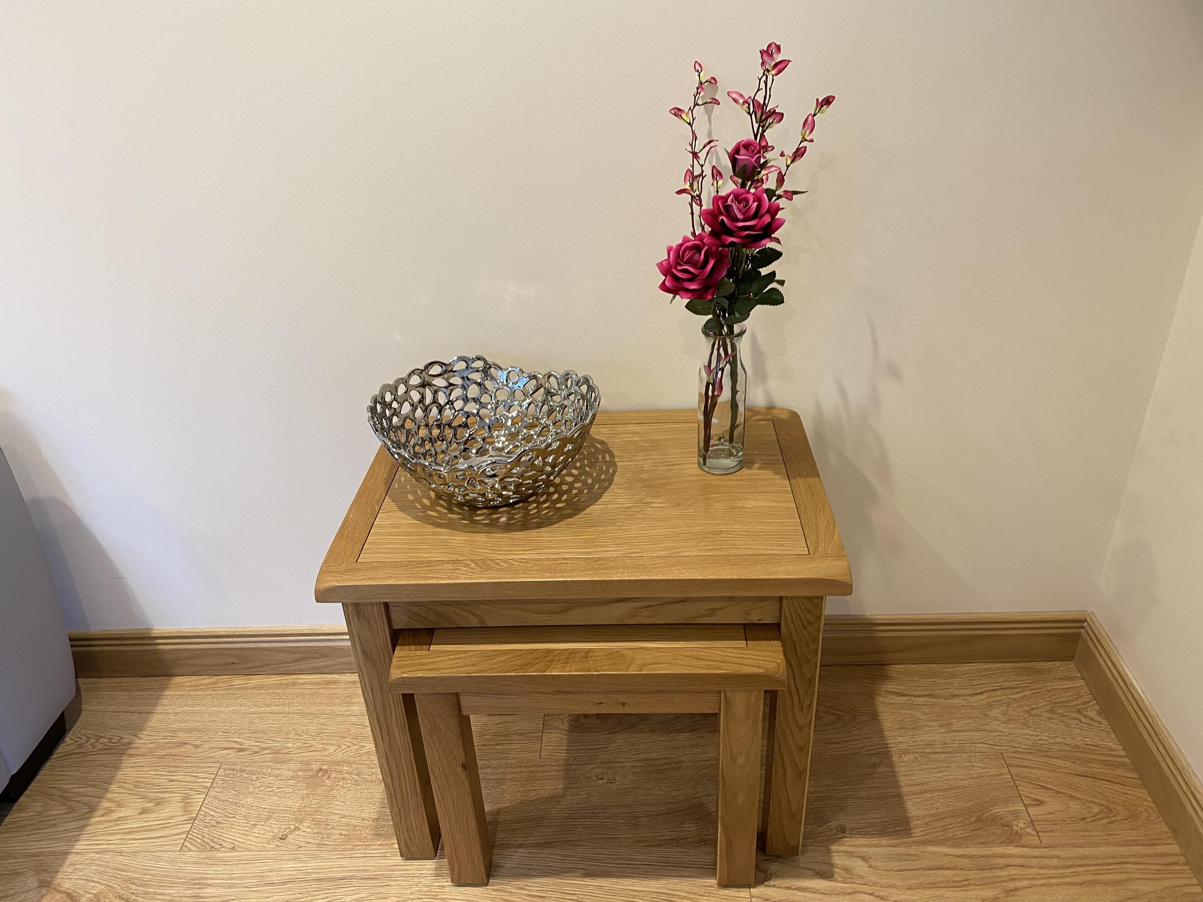 A wooden table with a decorative bowl and a vase with flowers.