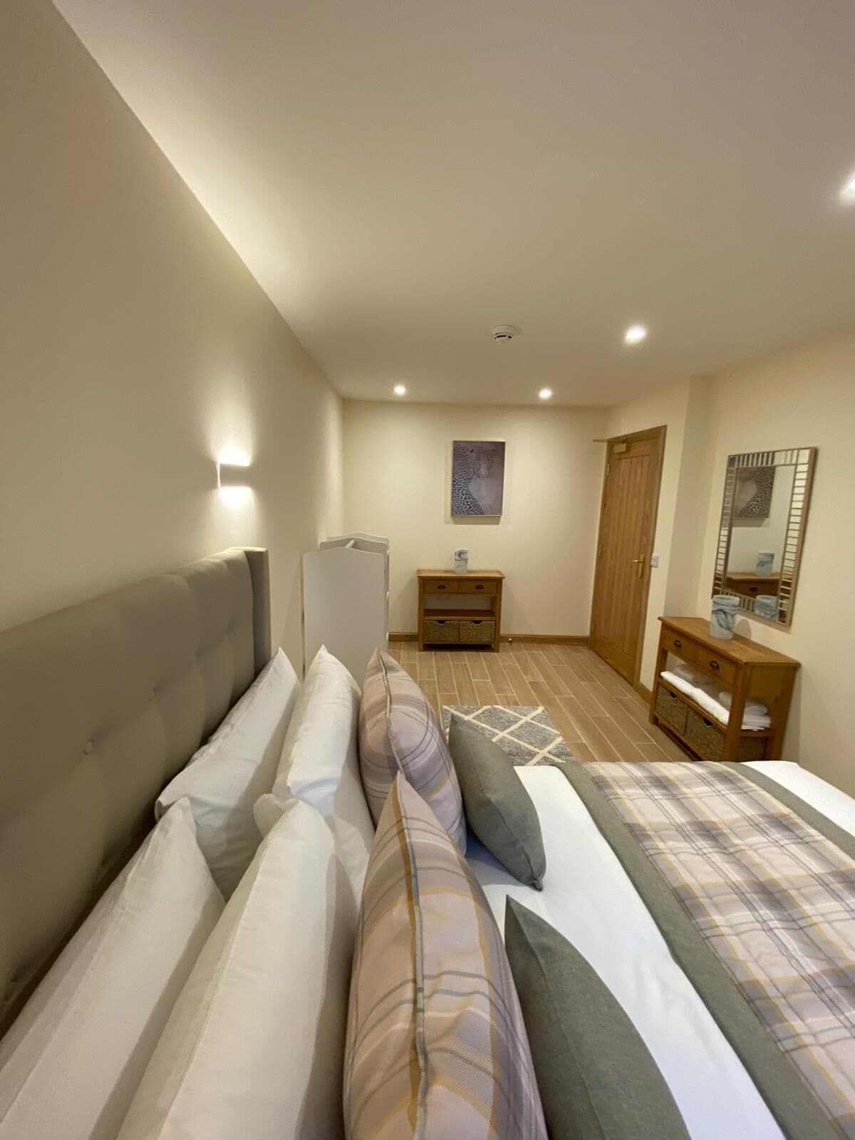 A bedroom with a large bed, a bedside table, a wardrobe, and a mirror on the wall.