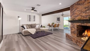 A modern living room with a fireplace, a sofa, a coffee table, and a dining area. - Brand New Hot Tub & Heated Pool, Perfect Location (Scottsdale)