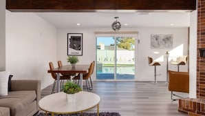 A modern living room with a dining area, a fireplace, and a view of a swimming pool. - Brand New Hot Tub & Heated Pool, Perfect Location (Scottsdale)