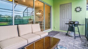 A modern outdoor seating area with a sofa, a glass table, and a barbecue grill. - 142cd-non Renting 4/1/2022 -festival Resort (Davenport)
