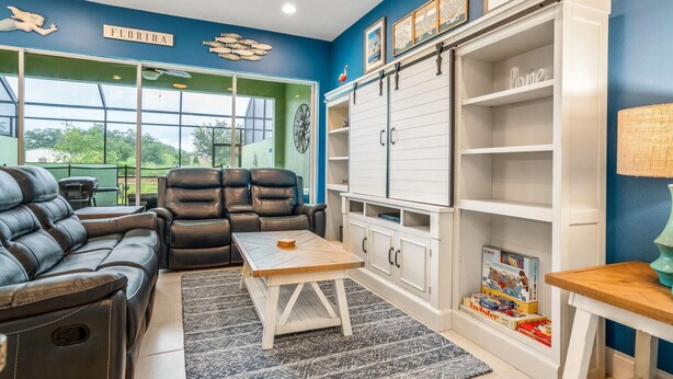 A room with a blue wall, a white cabinet, a black leather sofa, and a wooden coffee table. - 142cd-non Renting 4/1/2022 -festival Resort (Davenport)