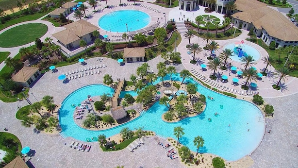 An aerial view of a resort with multiple swimming pools, sun loungers, and palm trees. - 1584mc-the Retreat at Championsgate (Davenport)