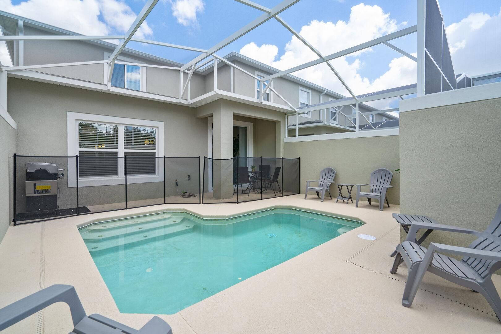 An indoor swimming pool with a glass ceiling, surrounded by Adirondack chairs and a covered seating area.