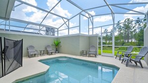 Piscina coberta com cadeiras e uma mesa, cercada por um compartimento de vidro.