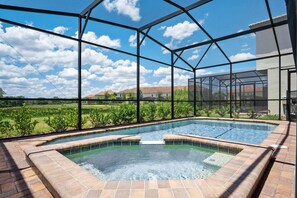Ein Schwimmbad mit Glasveranda, umgeben von einer Ziegelterrasse.