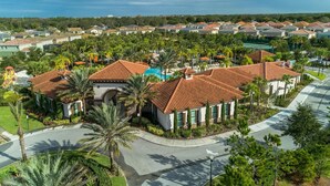 Un quartier résidentiel où les maisons se distinguent par leurs toits recouverts de tuiles rouges, et qui est agrémenté de palmiers et d’une piscine.