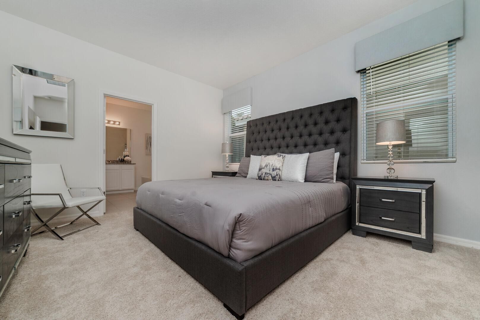 A modern bedroom with a large bed, a nightstand, a dresser, and a chair.