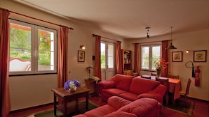 Una sala de estar con un sofá rojo, una mesita con un florero y una estantería.