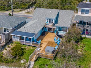 A coastal house with a wooden deck, outdoor seating, and a covered patio. - Surfside Cottage | Pet Friendly, Hot Tub, Views! (Topsail Beach)