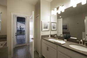 A modern bathroom with two sinks, a large mirror, and a door leading to a balcony.