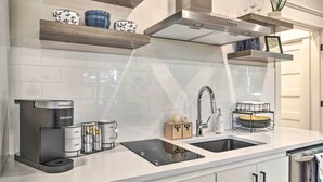 Eine moderne Küche mit integrierter Kaffeemaschine, einem Spülbecken und Holzregalen über der Arbeitsplatte.