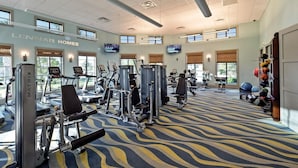 Un gimnasio con cintas de correr, máquinas de pesas y pelotas de ejercicio.
