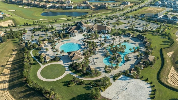 Ein Golfplatz mit mehreren Schwimmbecken, einem Clubhaus und gepflegter Landschaftsgestaltung.