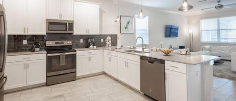 A modern kitchen with white cabinets, stainless steel appliances, and a dishwasher.