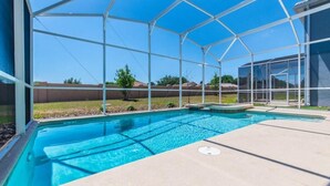 A swimming pool with a clear blue water, surrounded by a glass enclosure. - C1614mvd-the Retreat at Championsgate (Davenport)