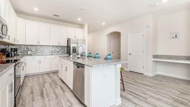 A modern kitchen with white cabinets, granite countertops, and a central island. - C1614mvd-the Retreat at Championsgate (Davenport)