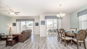 A spacious living room with a brown sofa, a dining table with chairs, and a ceiling fan. - C1614mvd-the Retreat at Championsgate (Davenport)