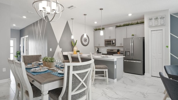 Een moderne keuken met witte kasten, een centraal eiland, roestvrijstalen apparatuur en een eethoek met witte stoelen en een marmeren vloer.