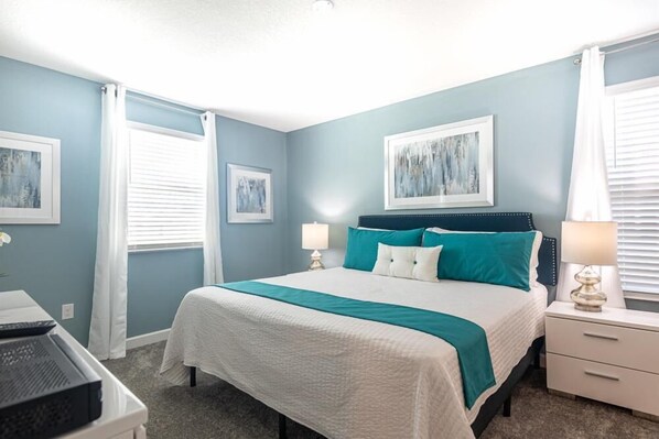 A bedroom with a bed, two bedside tables, and a window with curtains.