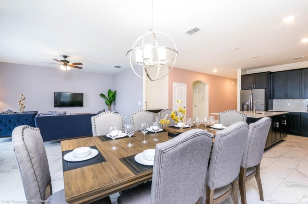 A modern dining room with a wooden table set for six, surrounded by upholstered chairs.