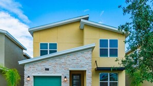 A two-story house with a stone facade, a green garage door, and a well-maintained lawn.