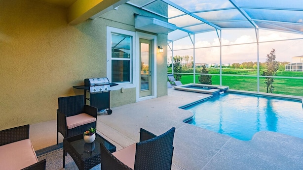 A covered outdoor area with a pool, a grill, and seating.