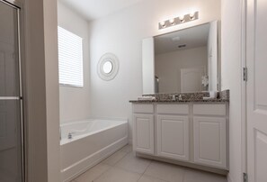 A modern bathroom with a freestanding bathtub, a vanity with a large mirror, and a round wall decoration. - 5268oba-solterra Resort (Davenport)