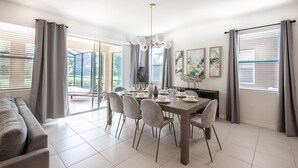 A dining area with a table set for six, surrounded by chairs, and a sofa in the foreground. - 5268oba-solterra Resort (Davenport)
