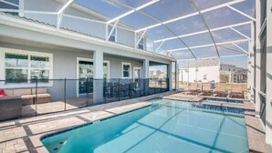 A covered outdoor swimming pool with a glass roof, surrounded by lounge chairs and a patio area. - 1533mc -non-renting The Retreat at Championsgate (Davenport)