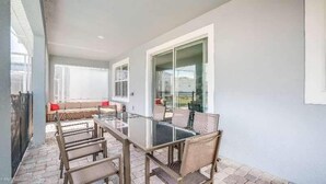 A patio with a glass table and chairs, a cushioned bench, and a view through a glass door. - 1533mc -non-renting The Retreat at Championsgate (Davenport)