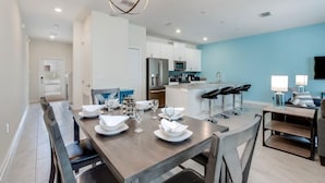 A modern kitchen with white cabinets, a stainless steel refrigerator, and a microwave. - C800pbd - The Retreat at Championsgate (Davenport)
