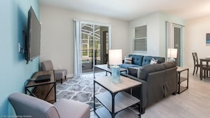 A modern living room with a sofa, a coffee table, and a TV mounted on the wall. - C800pbd - The Retreat at Championsgate (Davenport)