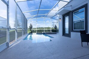 Ein moderner, überdachter Hallenpool, umgeben von großen Fenstern mit Blick ins Freie.