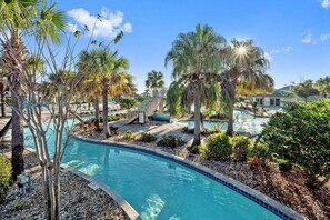 A swimming pool with a curved edge, surrounded by palm trees and a small bridge. - 570pbd-the Retreat at Championsgate (Davenport)