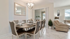 A dining area with a marble-tiled floor, a chandelier, and a dining table set for six. - 570pbd-the Retreat at Championsgate (Davenport)