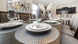 A dining area with a long table set for a meal, featuring white plates, clear glassware, and a decorative vase with white flowers. - 6049bod-solterra Resort (Davenport)