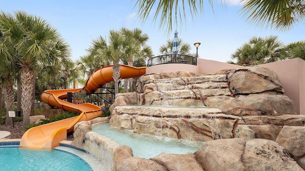 A water park with a multi-lane water slide, a pool, and palm trees. - 6049bod-solterra Resort (Davenport)