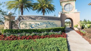 Señal de ChampionsGate con un arco de piedra y palmeras.