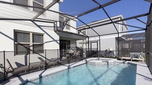 A swimming pool with a glass enclosure, outdoor furniture, and a clear blue sky. - 8912prw- NON Renting July 7, 2022 Windsor at Westside (Kissimmee)
