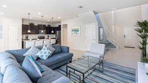 A modern living room with a sofa, a glass coffee table, and a staircase leading to an upper floor. - 8912prw- NON Renting July 7, 2022 Windsor at Westside (Kissimmee)