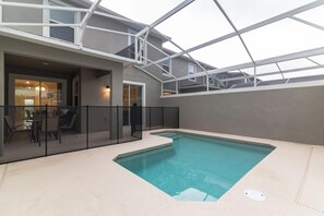 Une piscine intérieure dotée d’un toit en verre, entourée d’un espace aménagé avec des chaises et une table.