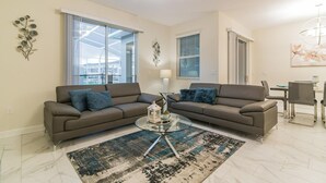 A living room with two sofas, a glass coffee table, and a patterned rug. - 560pb- The Retreat at Championsgate (Davenport)