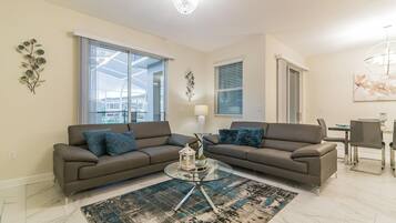 A living room with two sofas, a glass coffee table, and a patterned rug.