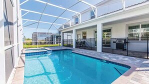 A swimming pool with a covered patio area, a barbecue grill, and a view of a residential neighborhood. - C9036sid-the Retreat at Championsgate (Davenport)